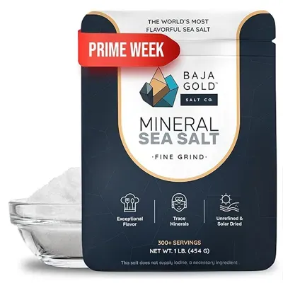 Black package labeled “Baja Gold Mineral Sea Salt Fine Grind” with icons and bowl of salt behind it.