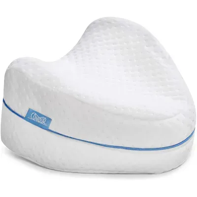 White contoured foam pillow with textured surface and curved shape, placed on a plain light background.